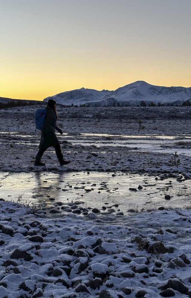 Naisen tumma, kävelevä siluetti lumisessa maastossa