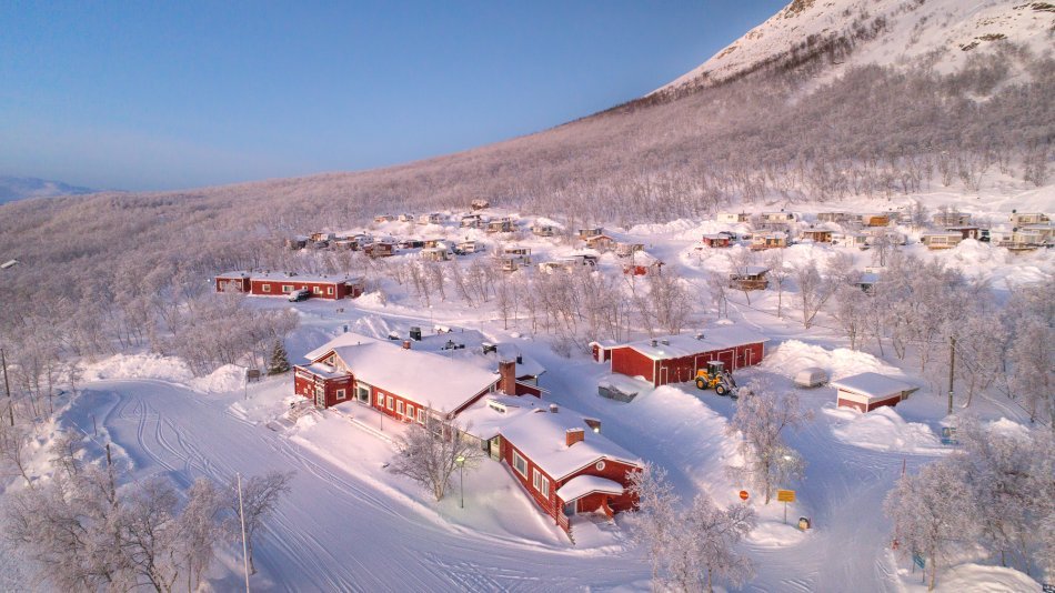 Kuvassa on Kilpisjärven Retkeilykeskuksen aluetta kuvattu ylhäältä päin talvisena päivänä aurigon laskiessa.