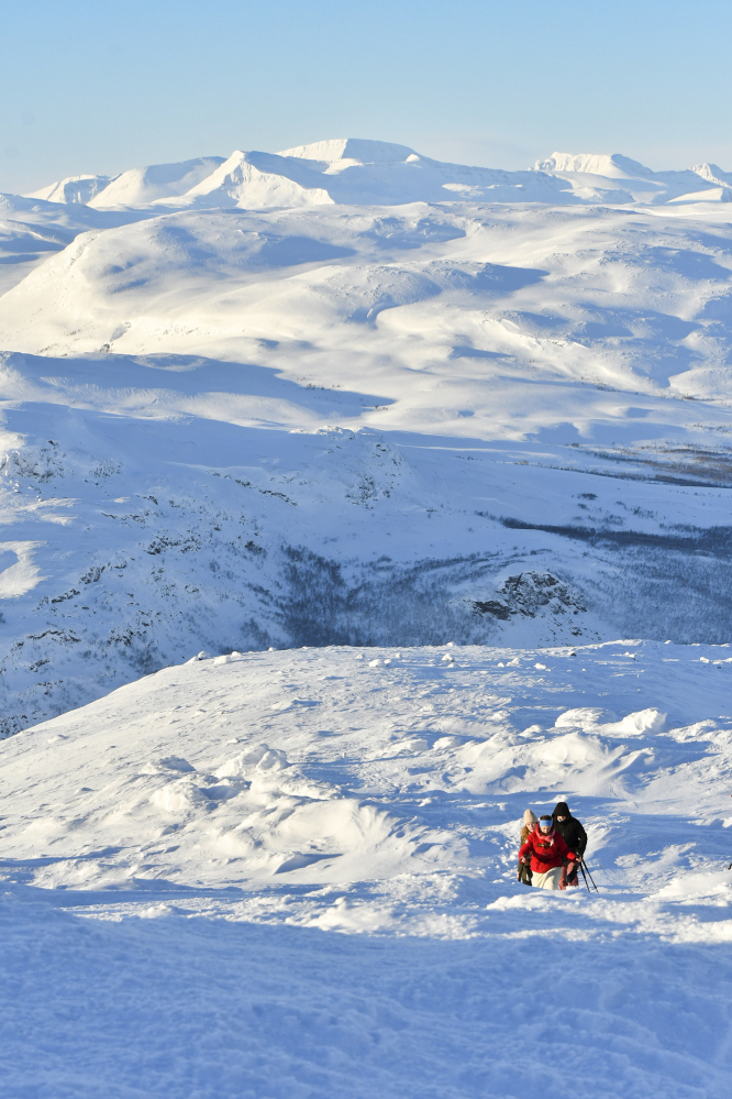 Ihmisiä lumikenkäilemässä kohti Saanatunturin huippua vuoret taustallaan