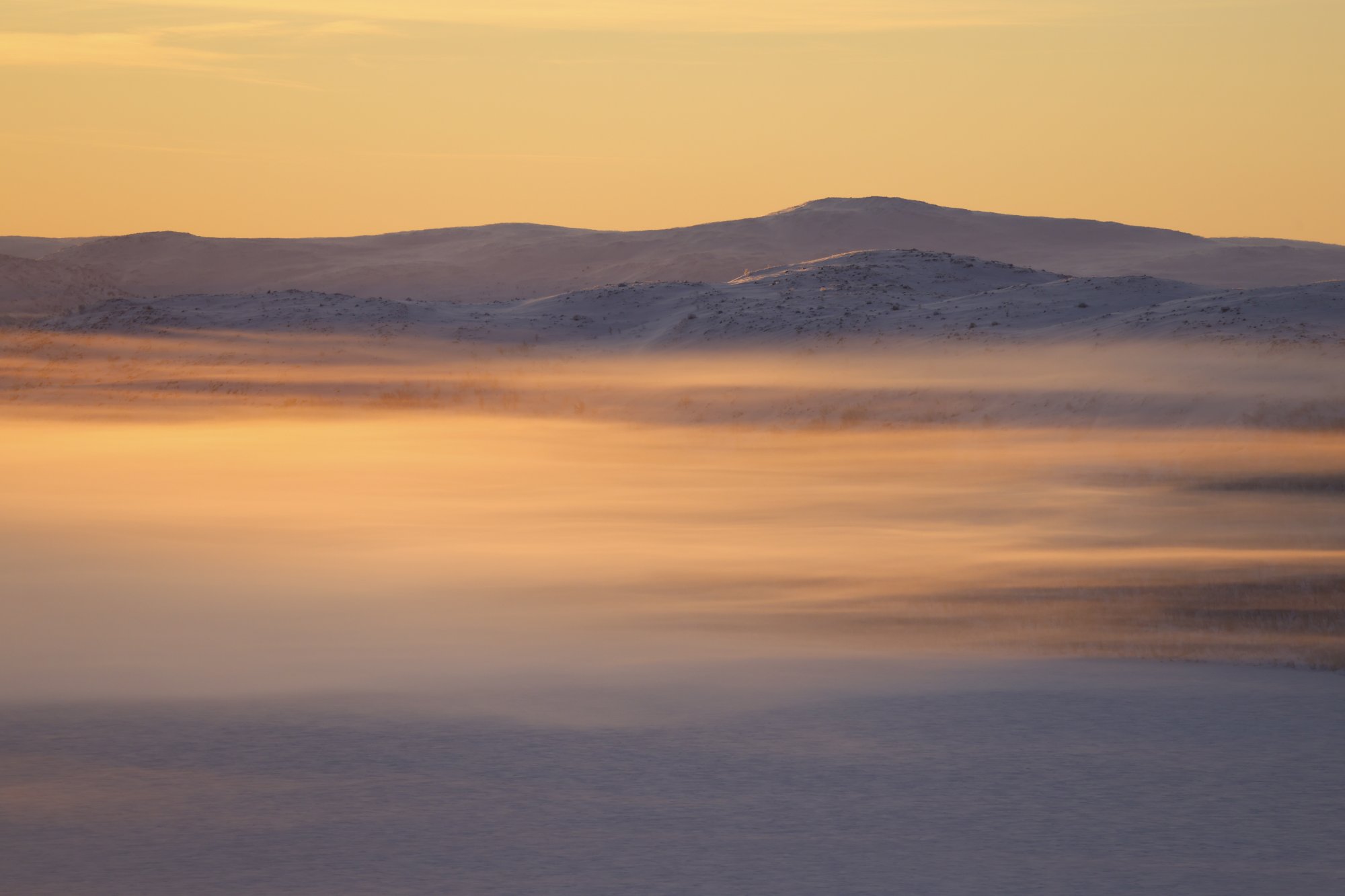 Aurinko värjää pakkasusvan hehkuvan oranssiksi Kilpisjärven yllä.