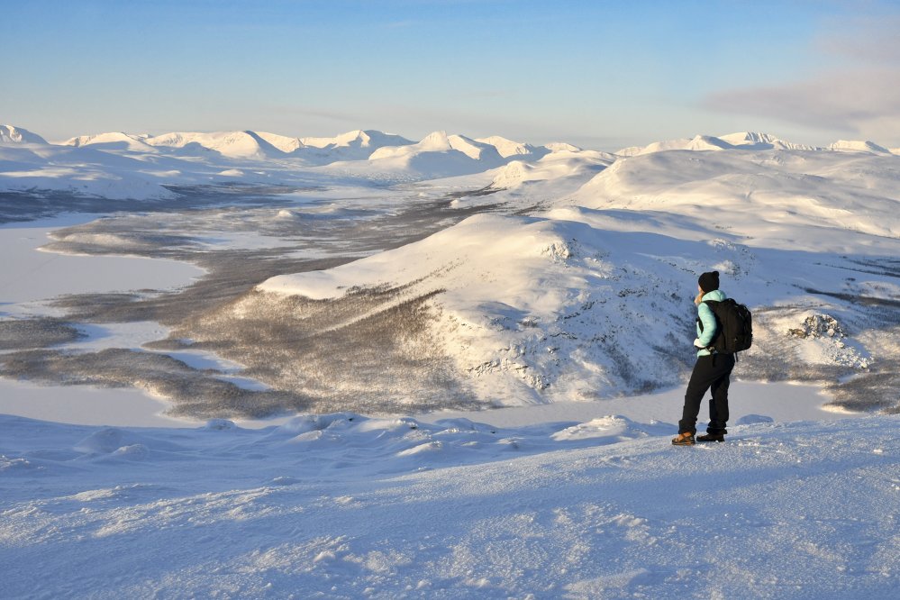Nainen katselee pikku-Malla aamuauringon valaistessa kaukaisuuteen jatkuvia tuntureita.