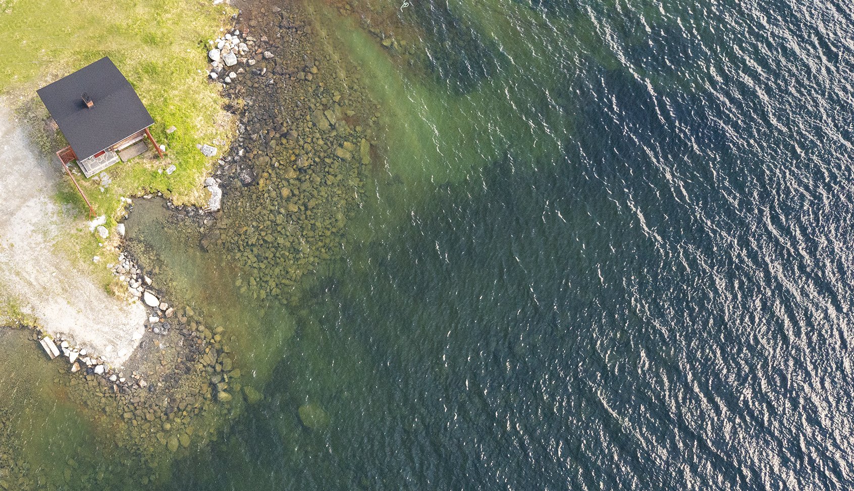 Kilpisjärven Retkeilykeskuksen perinteinen itselämmitettävä puusauna Kilpisjärven rannassa kuvattuna ylhäältä päin kesällä