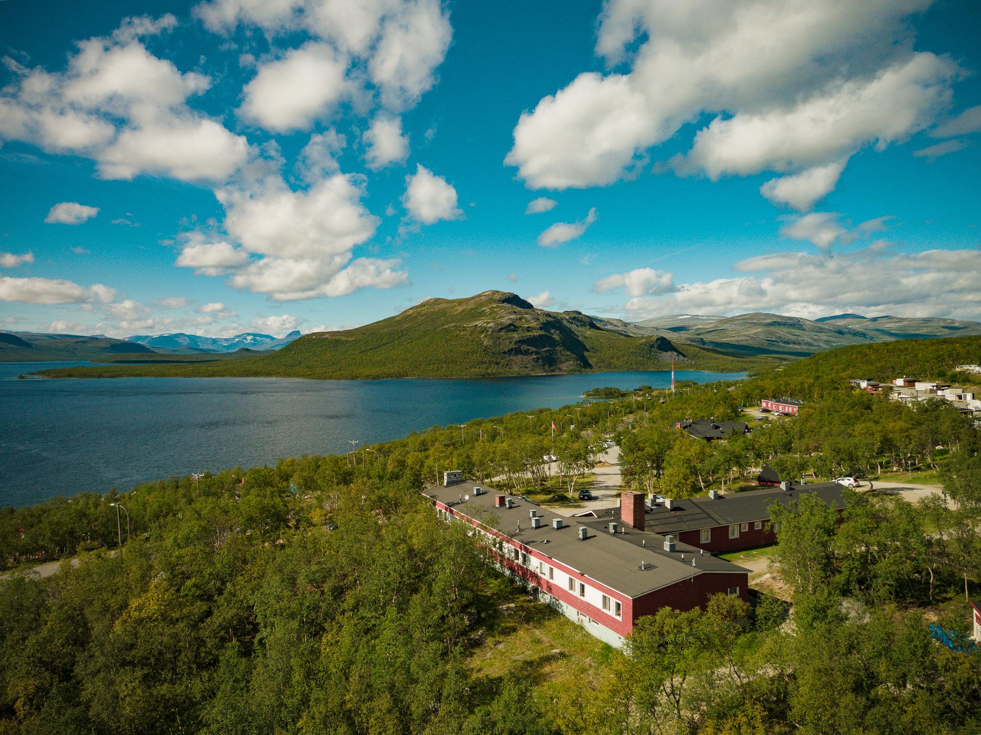 Kilpisjärven Retkeilykeskus Kilpisjärven rannalla, Mallan luonnonpuisto vastarannalla aurinkoisena kesäpäivänä.