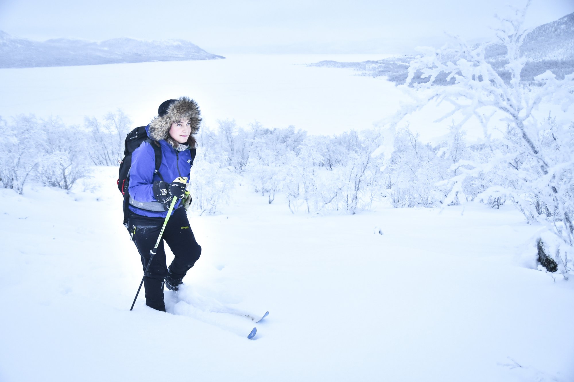 Anniina hiihtää tunturisuksilla karvalakki päässään hangessa lumisessa maisemassa