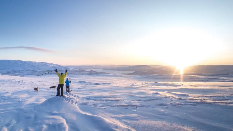 hiihtäjiä Kilpisjärvellä tunturissa tunturisuksilla auringonlaskun aikaan