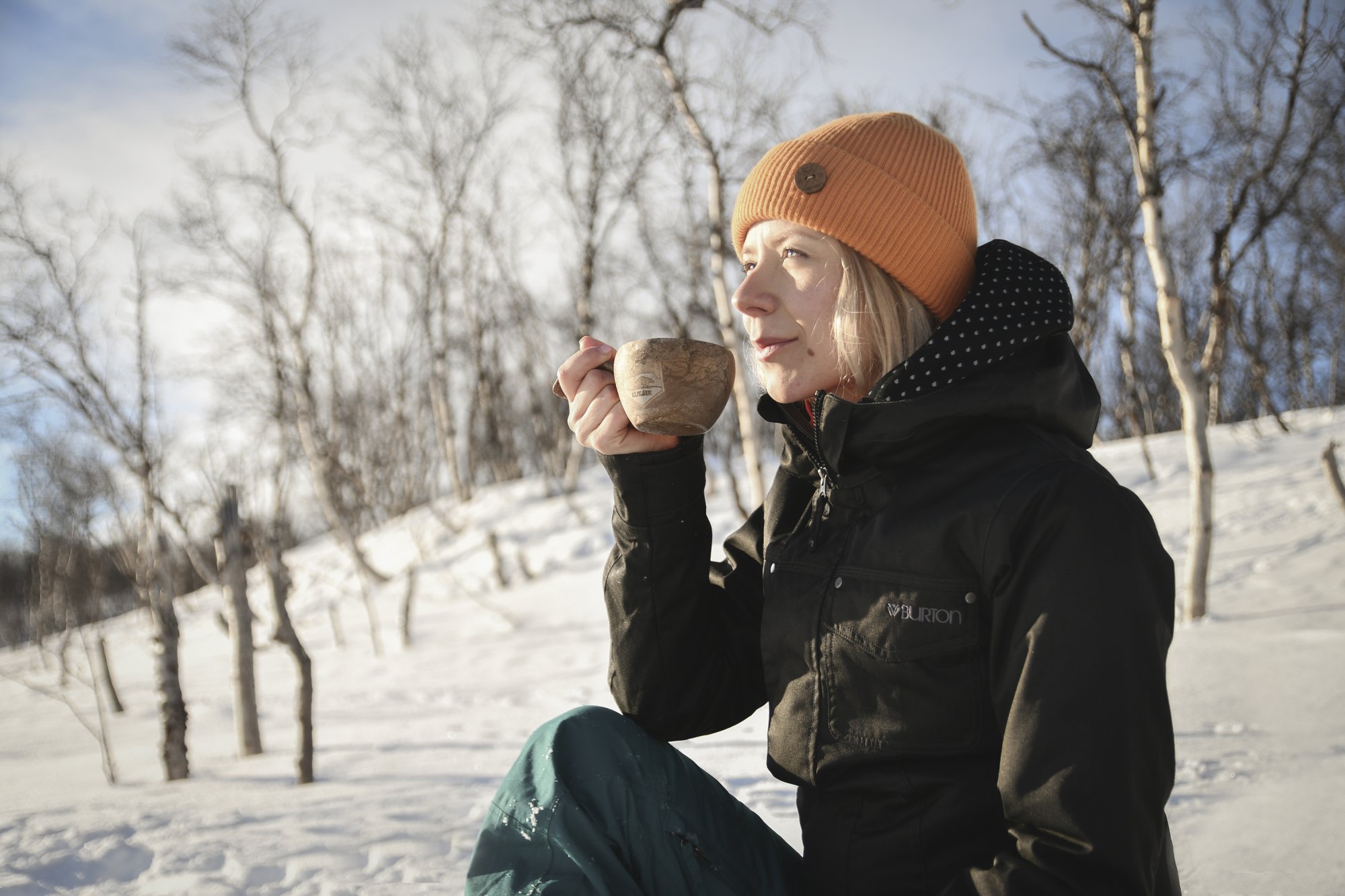 Nainen juo kuumaa juomaa hiihtoretkellä Kilpisjärvi Kupilkasta