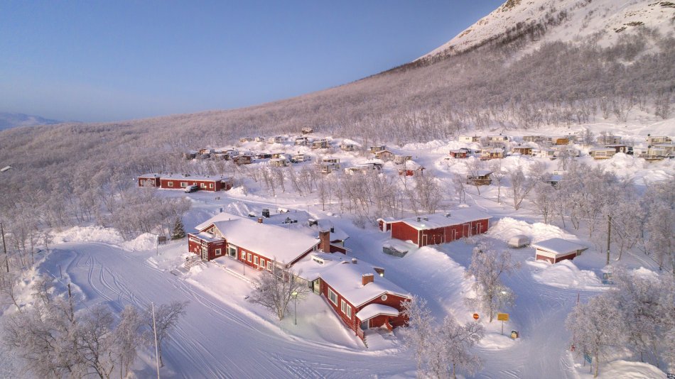 Kilpisjärven Retkeilykeskus talvella lumihankien keskellä pastellisessa talvimaisemassa Saanan juurella.