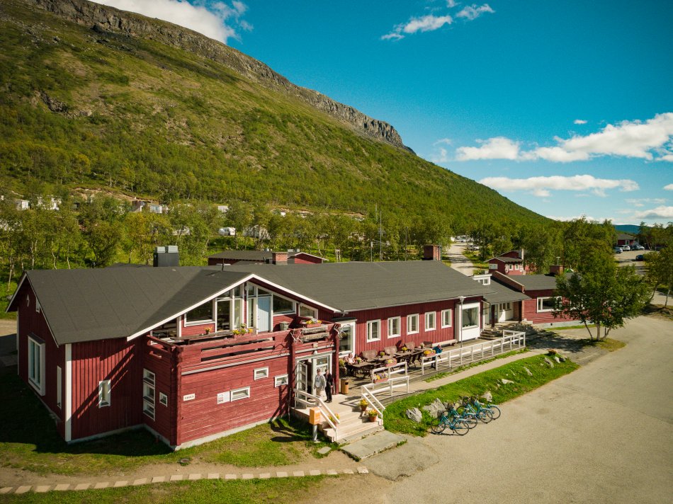 Kilpisjärven Retkeilykeskuksen punainen päärakennus Saanan juurella aurinkoisena kesäpäivänä.